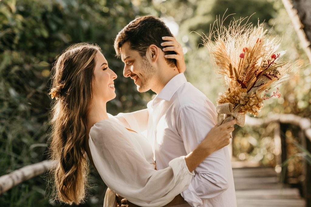 Eco-conscious wedding, happy couple hugging outdoors, bride holding dried bouquet