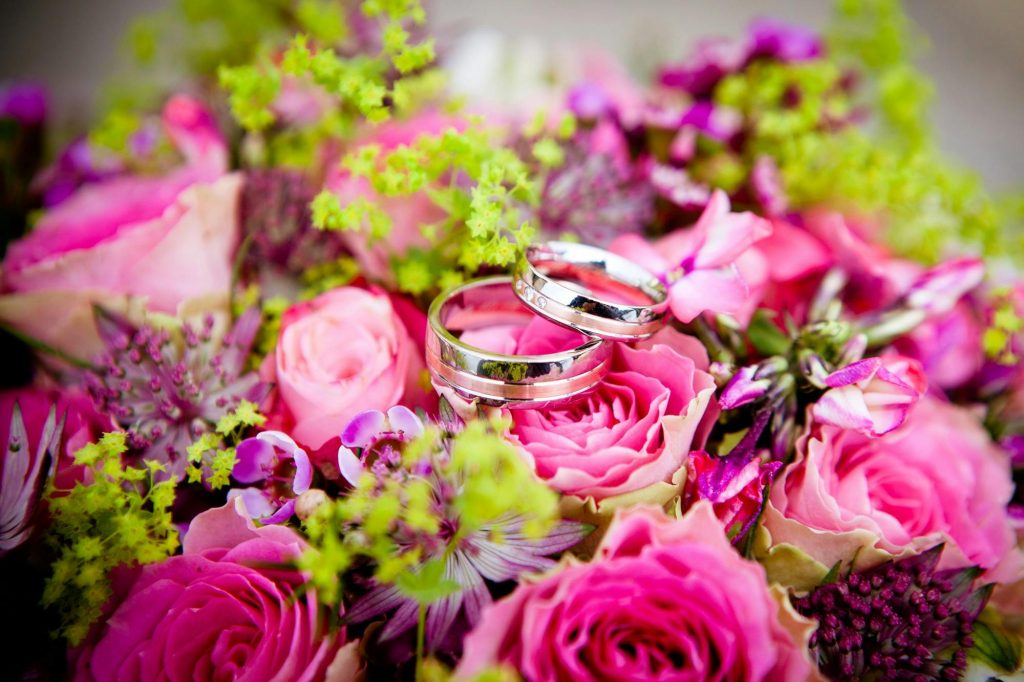 floral fantasy wedding, wedding rings placed on top of pink flowers