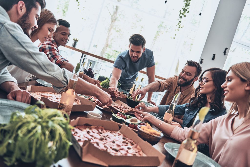 Great food and company. Group of young people in casual wear eating and smiling while having a dinner party