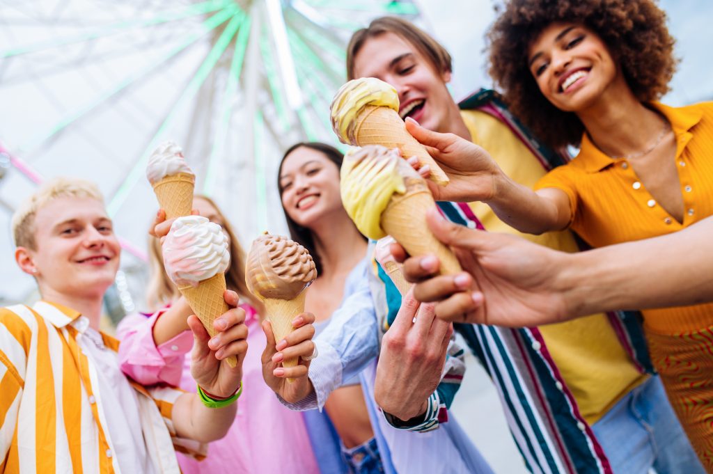 Multiracial young people together meeting at amusement park and eating ice creams - Group of friends with mixed races having fun outdoors - Friendship and lifestyle concepts