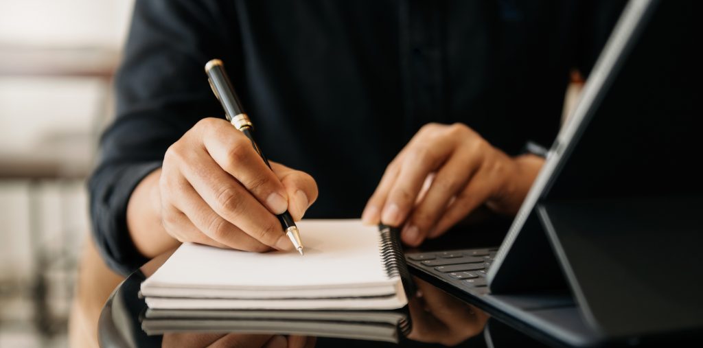 businessman hand working with new modern computer and writing on the notepad strategy diagram as concept morning light