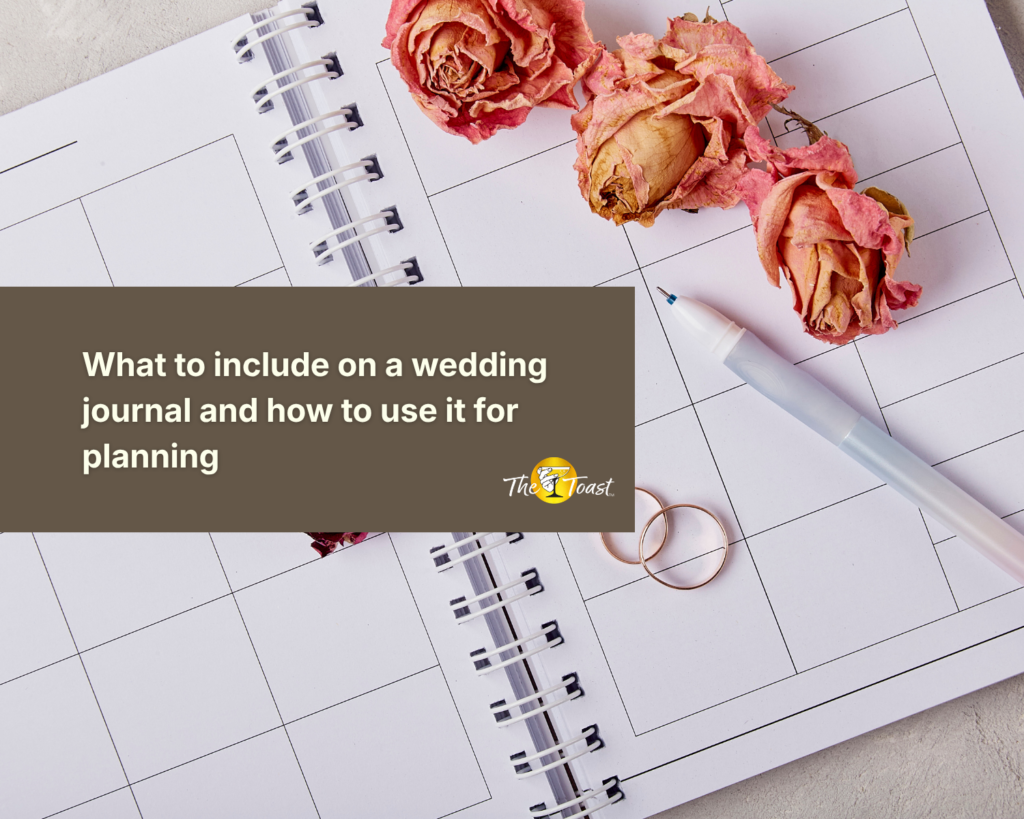 Wedding journal – open spiral planner with dried roses, wedding rings, and a pen on a white desk