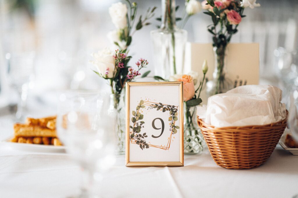 A wedding table decorations with flowers and a frame with the number 9 on it.