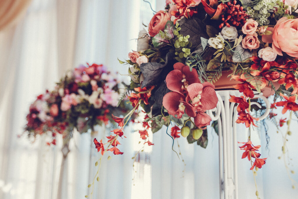 Bright floral displays in shades of pink and red create a romantic setting for a daytime event.