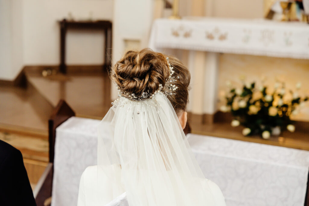 back of bride and groom sitting at wedding ceremony in church, brides luxury hairstyle