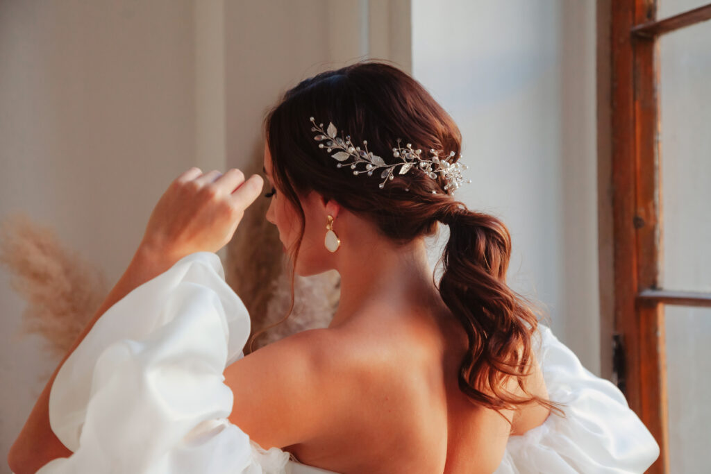 Portrait stylish bride young woman in white wedding dress standing at window, rear view. Bride female in vintage room, grey wall background in studio. Fashion style concept. Copy text space